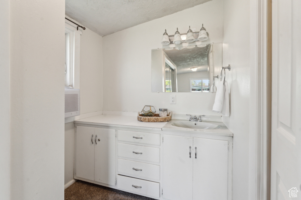 Bathroom featuring vanity, a textured ceiling, and healthy amount of natural light
