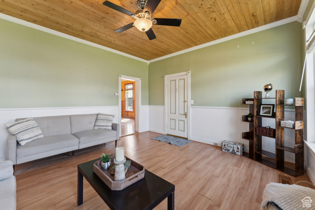 Living area featuring crown molding, wainscoting, a ceiling fan, wood ceiling, and wood finished floors
