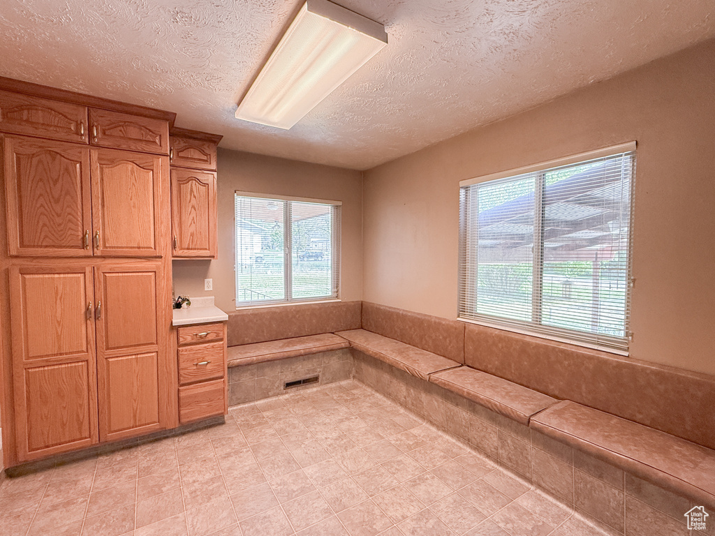 Unfurnished office featuring a textured ceiling, healthy amount of natural light, and light tile patterned floors