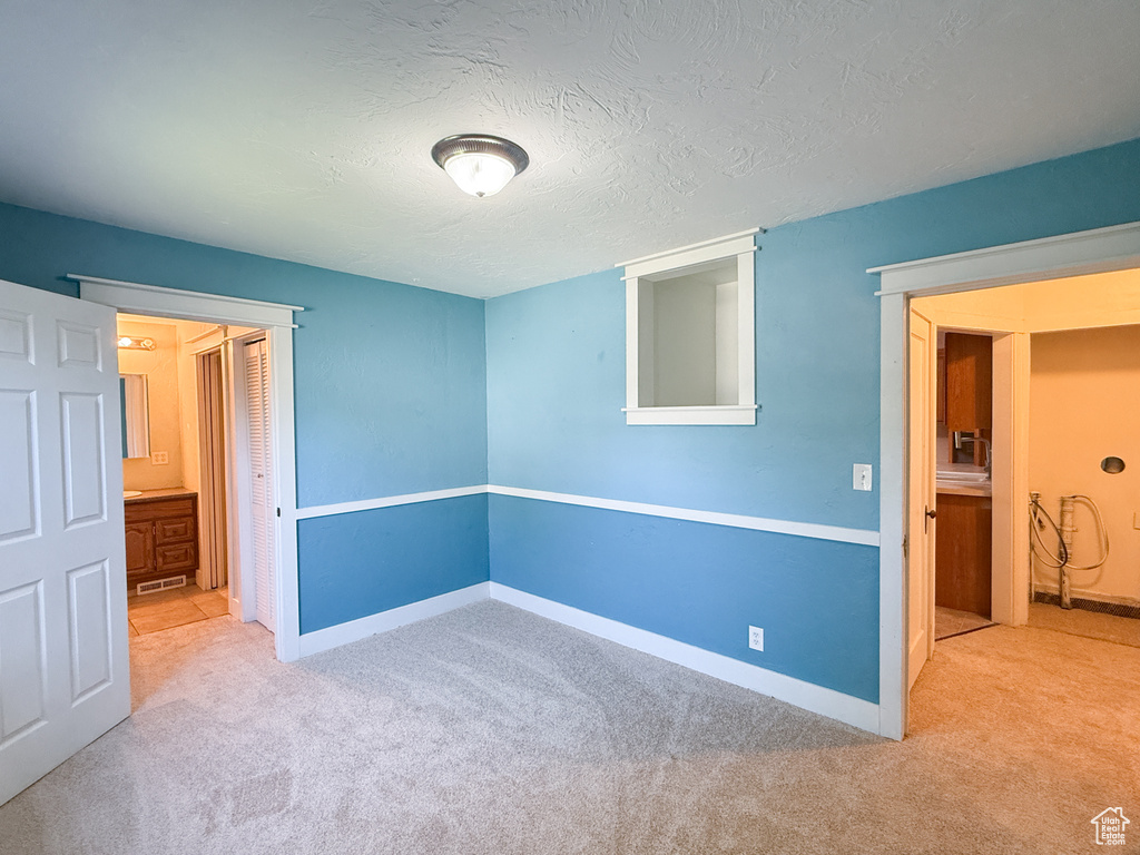 Unfurnished bedroom featuring carpet, baseboards, a textured ceiling, and a closet