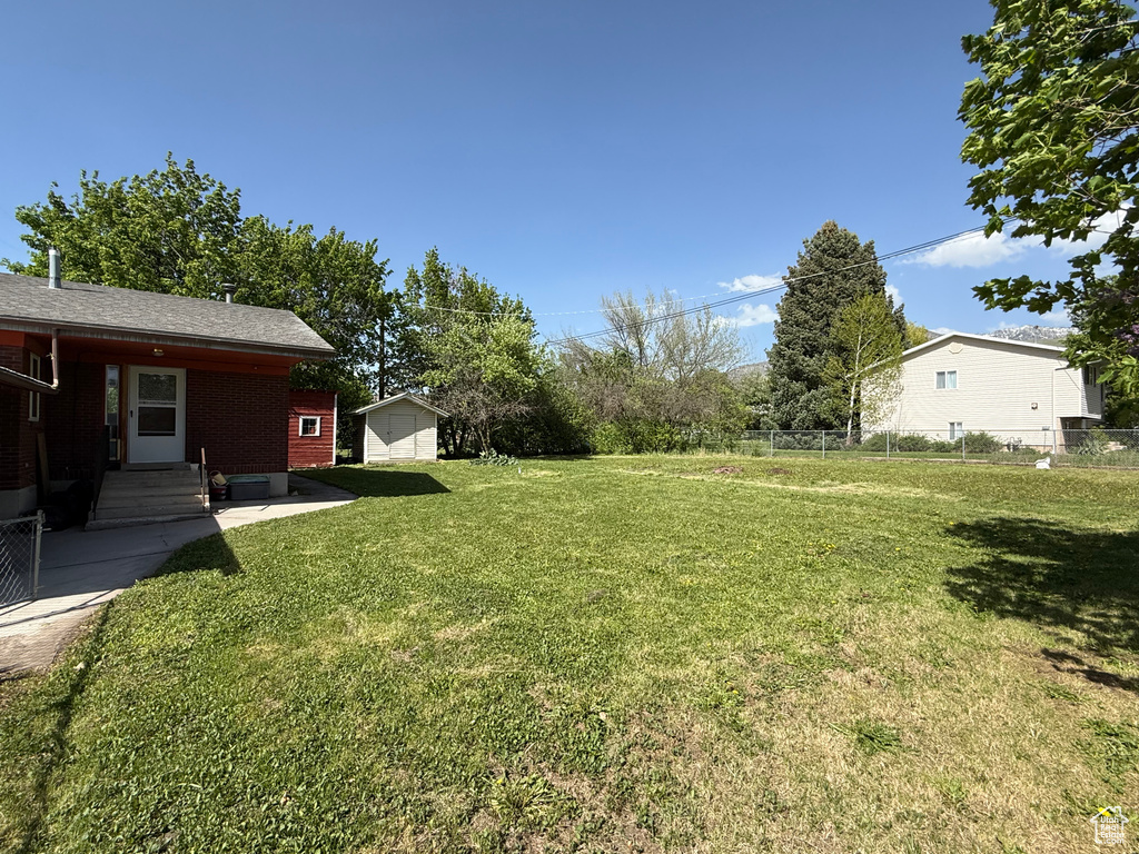 View of yard featuring entry steps, a storage unit, an outbuilding, and a patio area