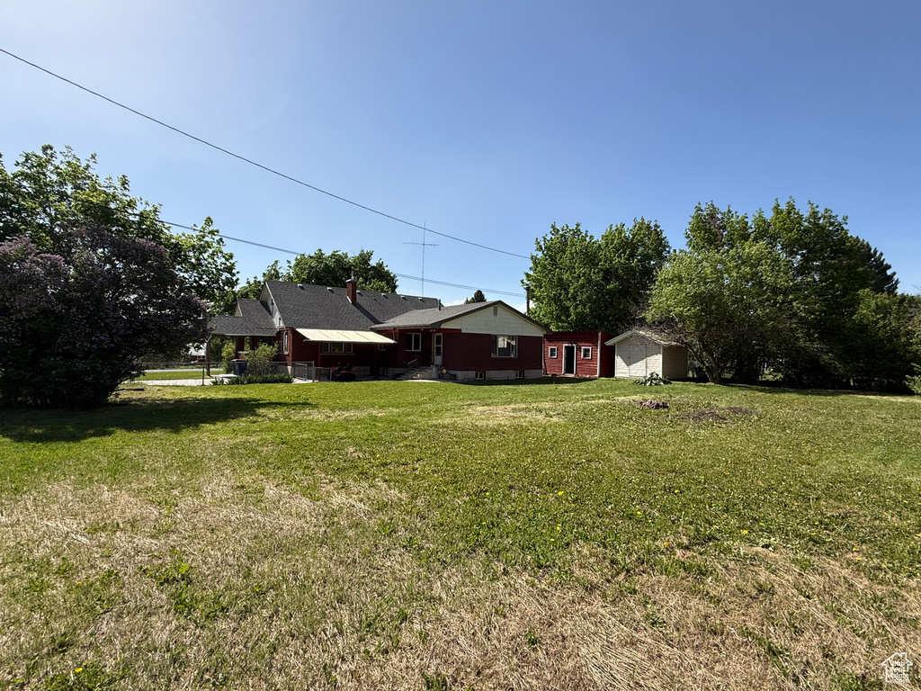 View of green lawn featuring a storage unit and an outdoor structure