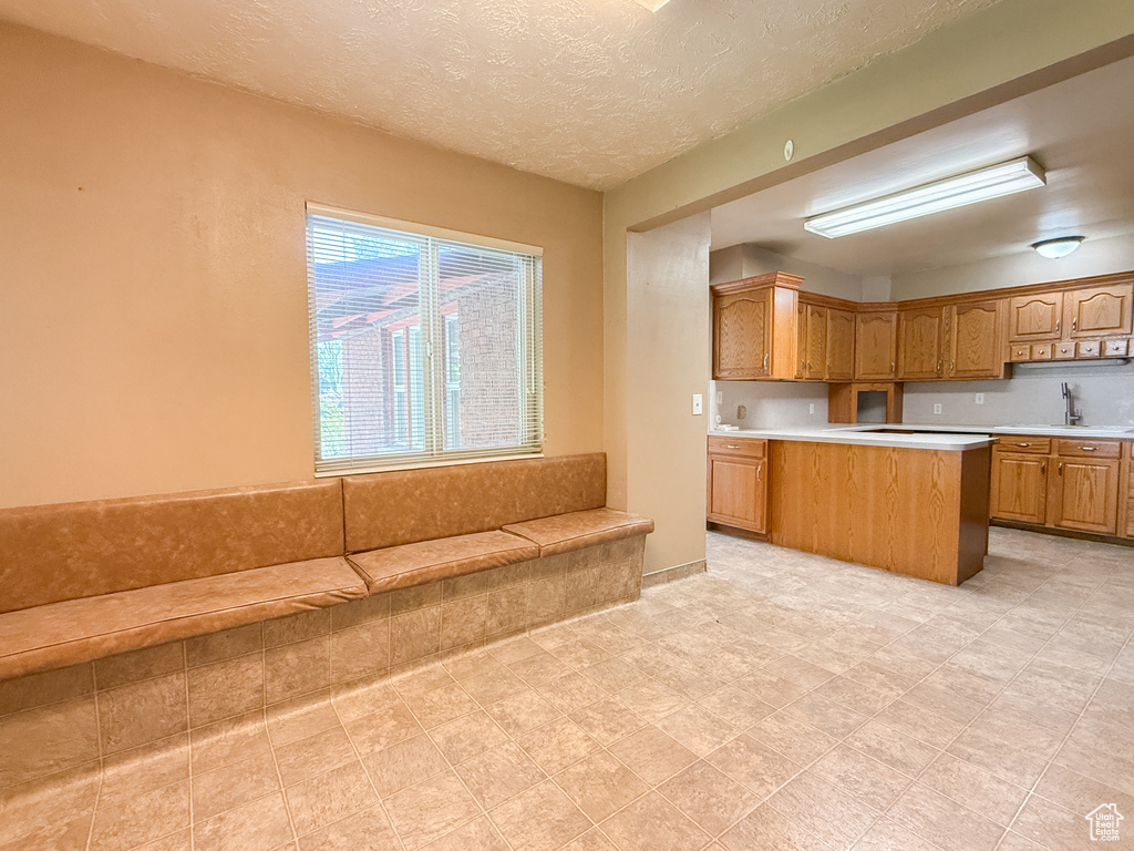 Kitchen featuring light countertops, brown cabinetry, a sink, and a textured ceiling
