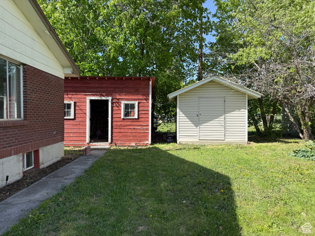 View of green lawn featuring an outdoor structure and a storage unit