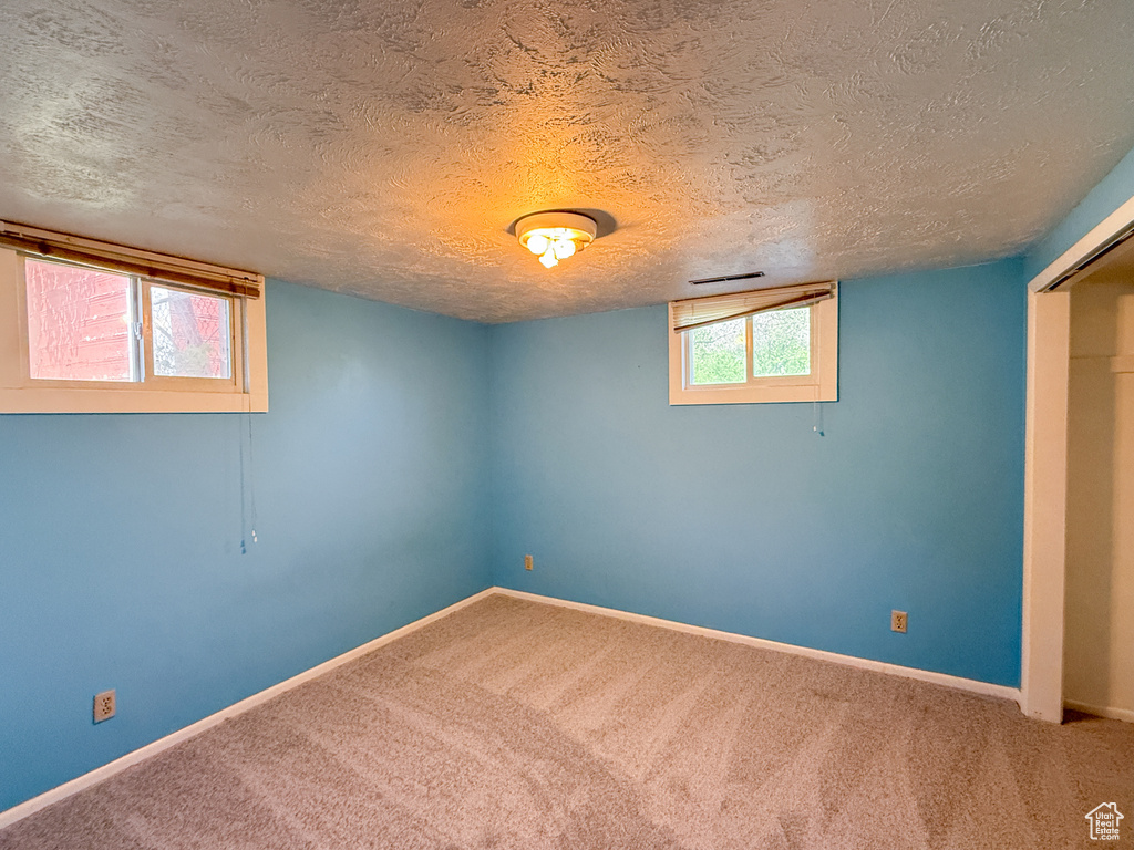 Basement with carpet floors, baseboards, and a textured ceiling