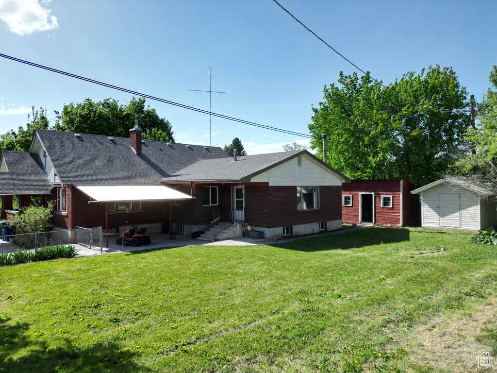 Rear view of house featuring entry steps, a patio, a shed, and an outbuilding