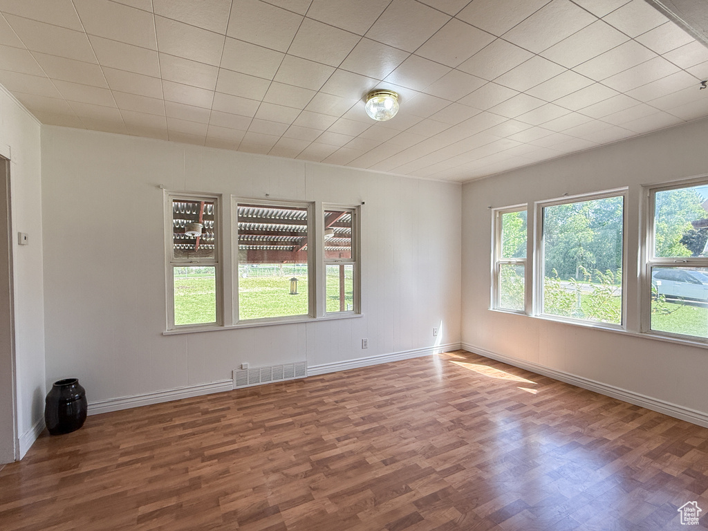 Empty room featuring plenty of natural light, wood finished floors, and baseboards