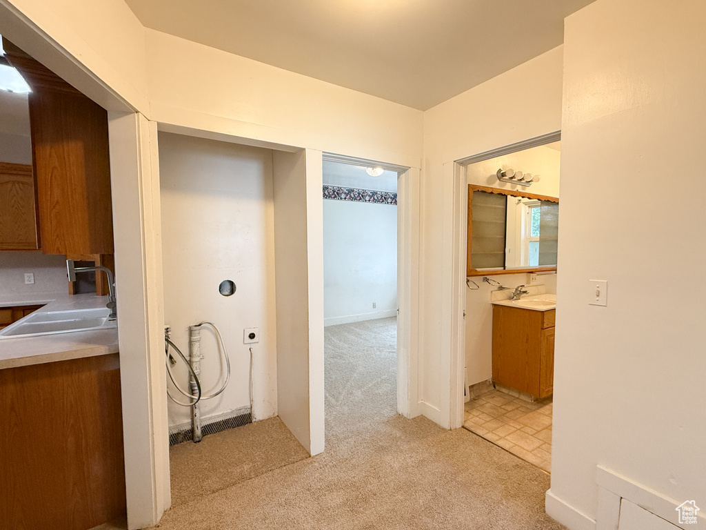 Hallway with a sink and light colored carpet