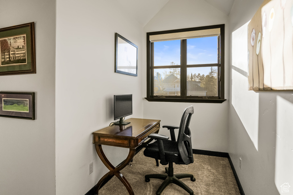 Carpeted home office with vaulted ceiling and baseboards