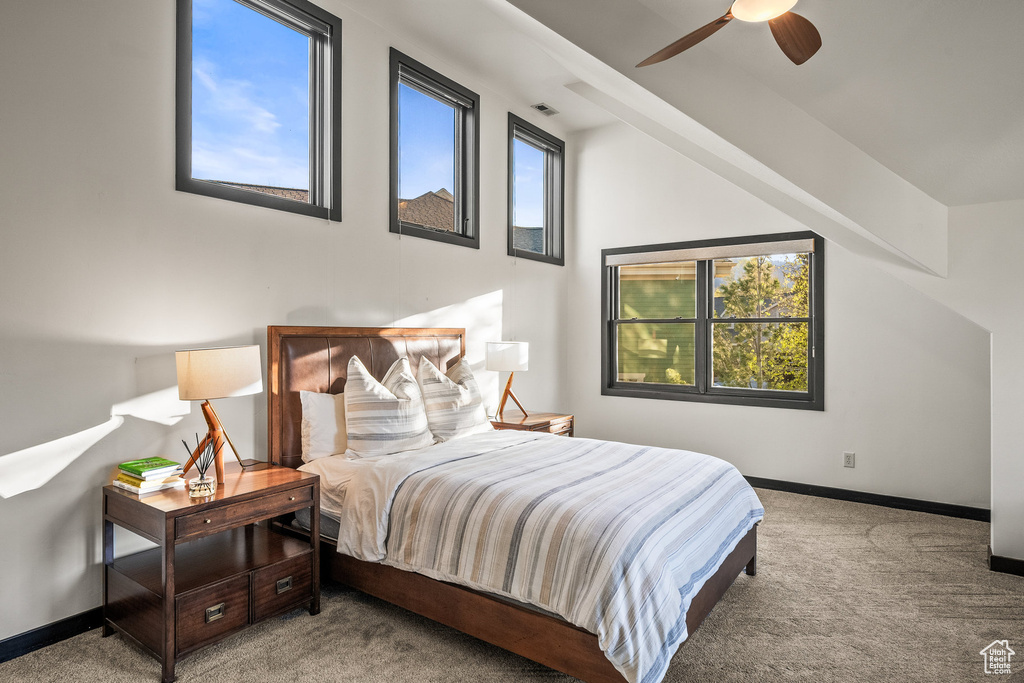 Bedroom featuring carpet, multiple windows, baseboards, lofted ceiling, and ceiling fan