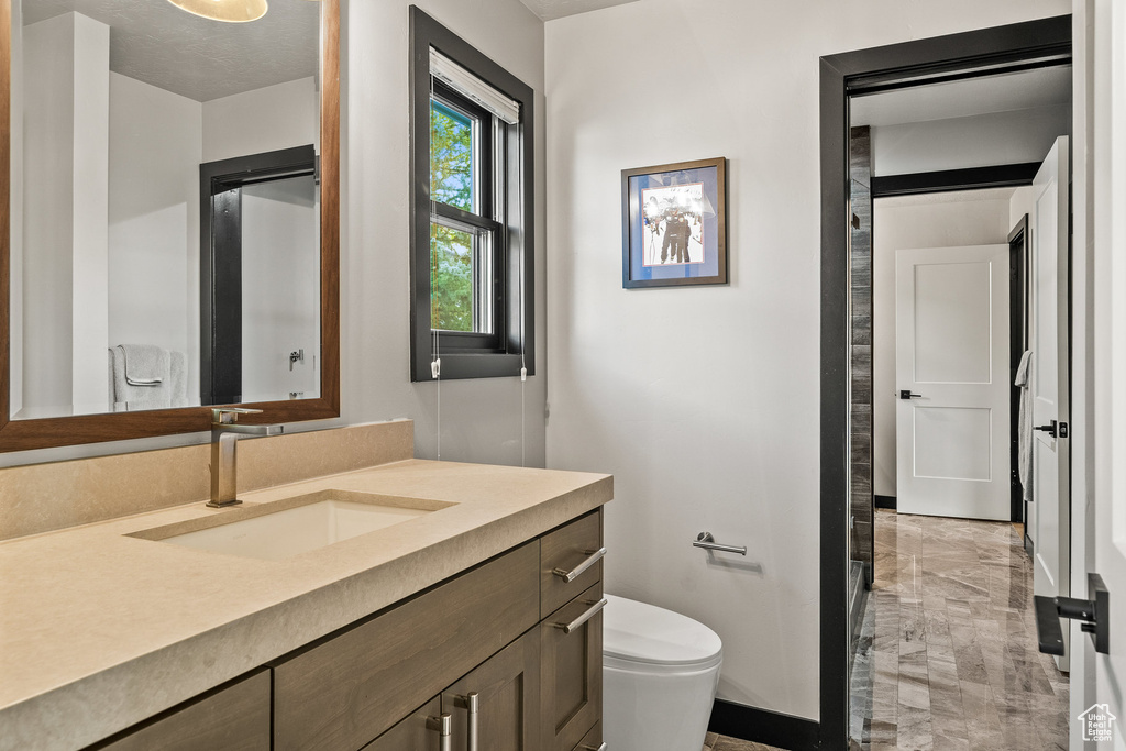 Bathroom with toilet, vanity, and baseboards