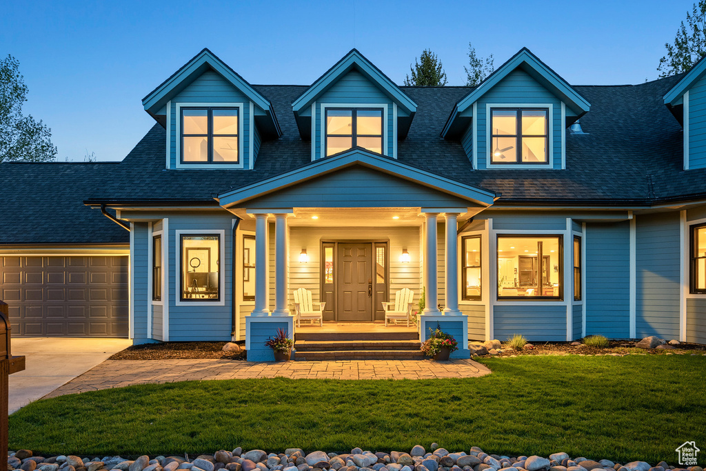 Cape cod home with covered porch, concrete driveway, a shingled roof, and a front lawn