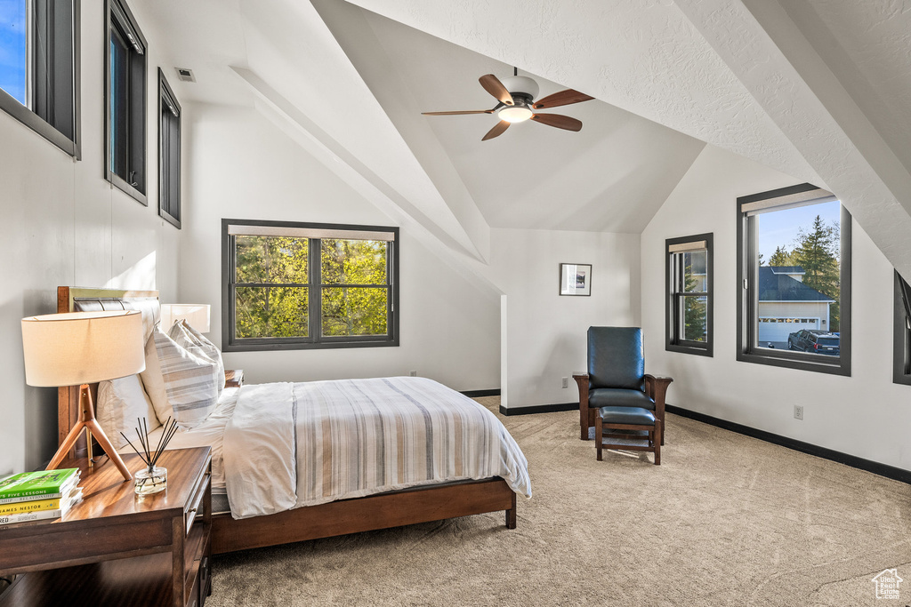 Carpeted bedroom featuring vaulted ceiling, multiple windows, and baseboards