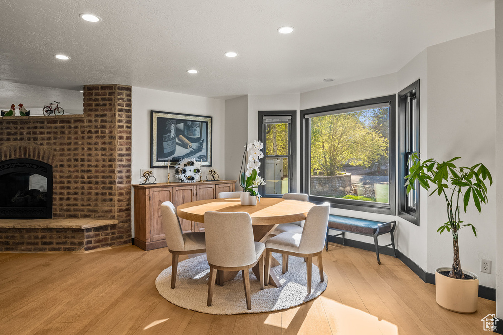Dining area with light wood finished floors, recessed lighting, baseboards, and a fireplace