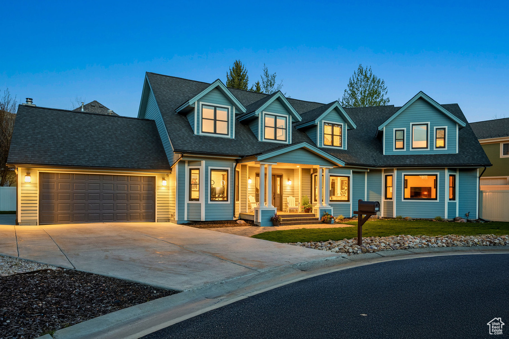 View of front of house featuring a garage, concrete driveway, a front yard, covered porch, and a shingled roof