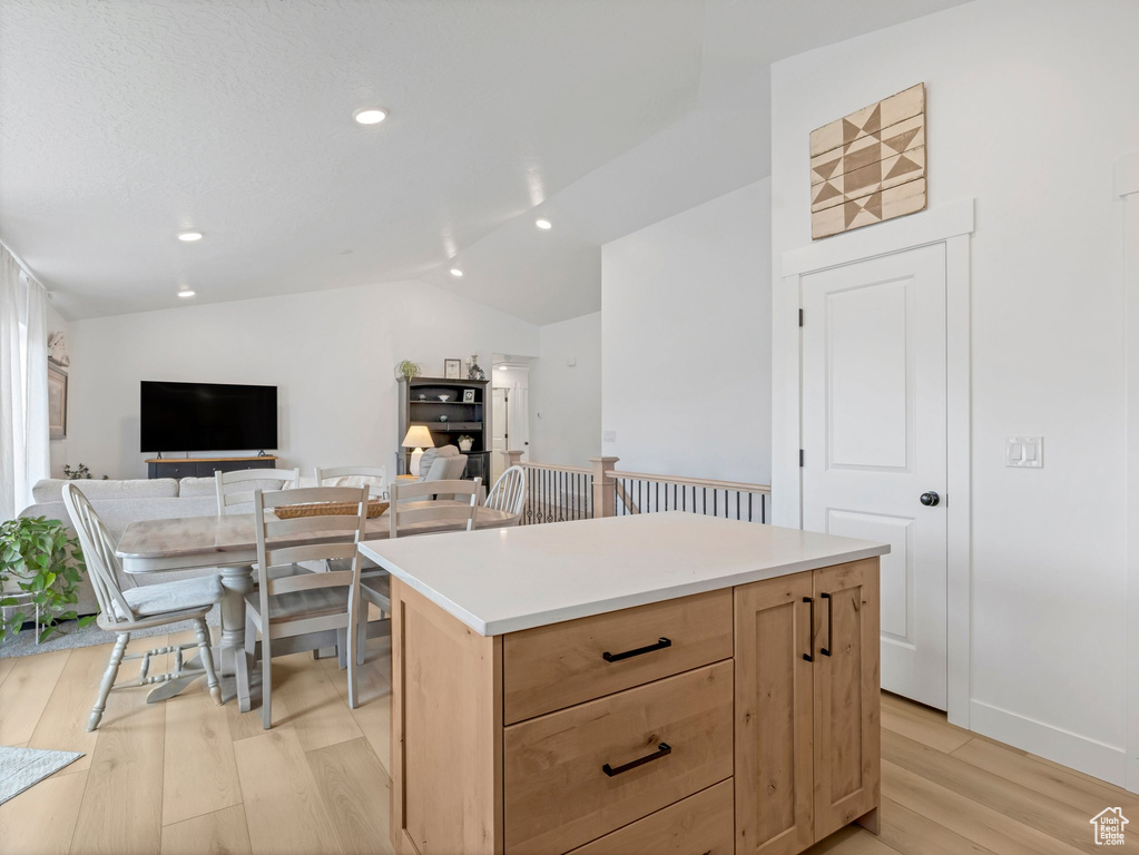 Kitchen with light wood-style flooring, light brown cabinets, vaulted ceiling, a center island, and recessed lighting
