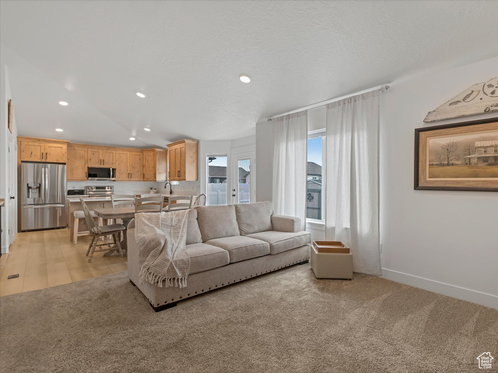Living area with recessed lighting, light carpet, and baseboards