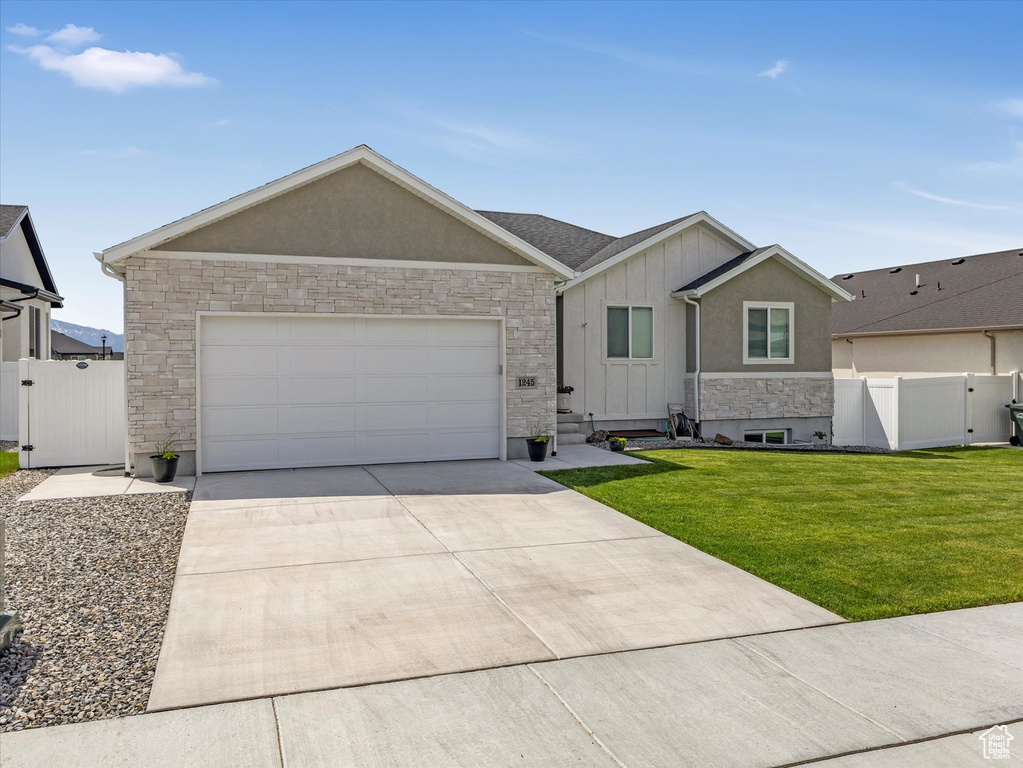 Ranch-style home with a gate, stone siding, concrete driveway, board and batten siding, and a garage