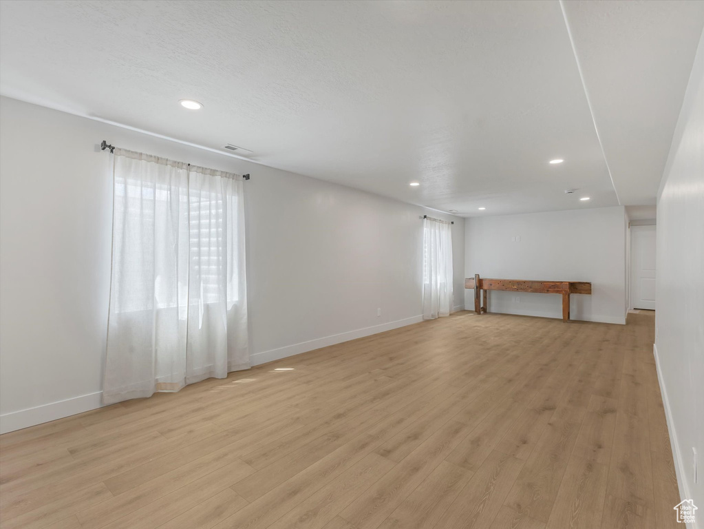 Unfurnished living room with recessed lighting, light wood-type flooring, and baseboards