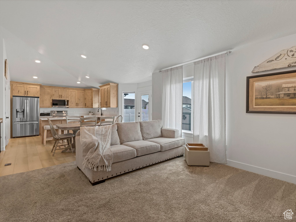 Living room with recessed lighting, lofted ceiling, baseboards, and light carpet