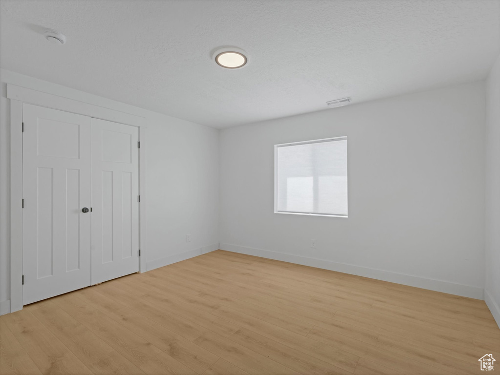 Unfurnished bedroom with light wood-style flooring, baseboards, and a closet