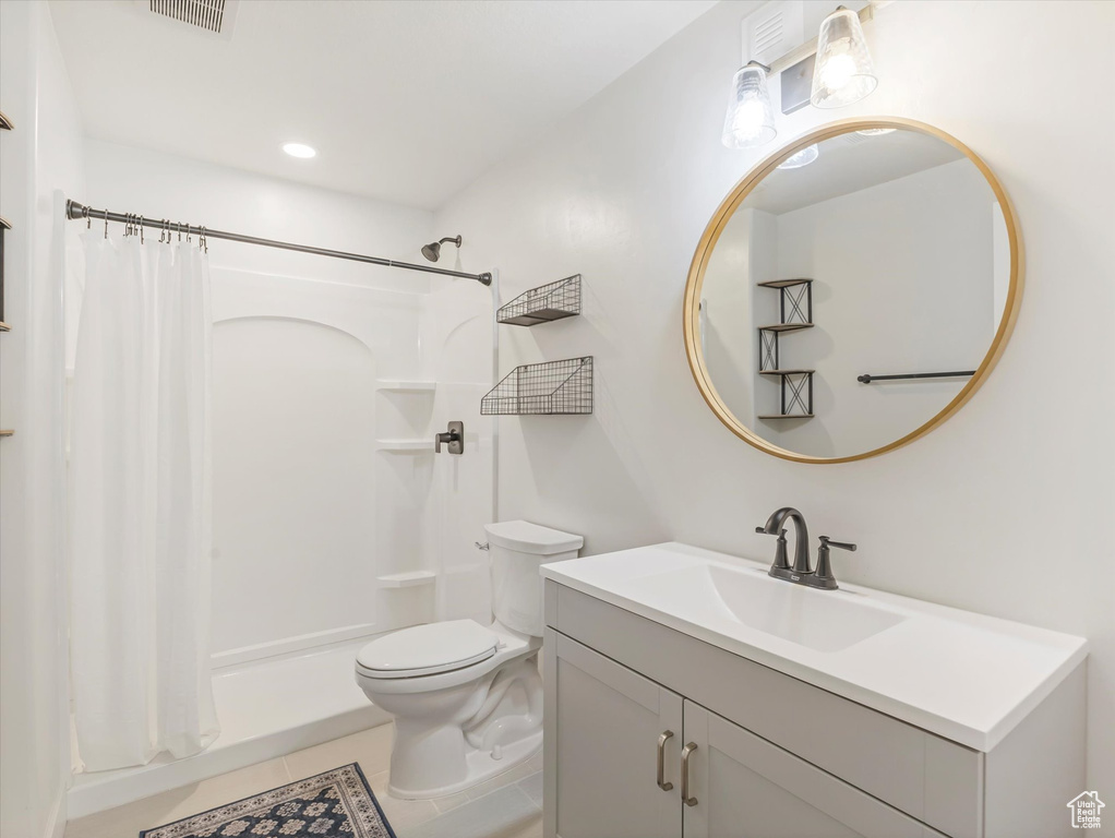 Bathroom with toilet, a shower with shower curtain, tile patterned floors, and vanity