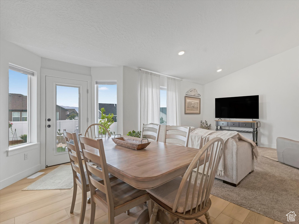 Dining space with healthy amount of natural light, light wood-type flooring, recessed lighting, baseboards, and vaulted ceiling