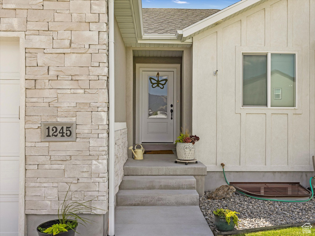 Property entrance featuring a shingled roof and stone siding
