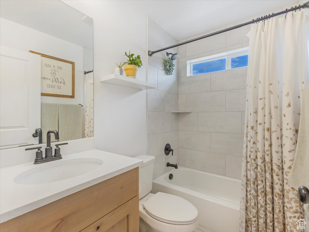 Bathroom with toilet, shower / tub combo with curtain, and vanity