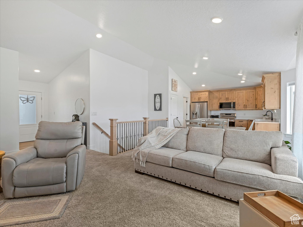 Living area with lofted ceiling, light colored carpet, and recessed lighting