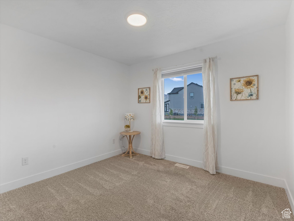 Empty room featuring light carpet and baseboards