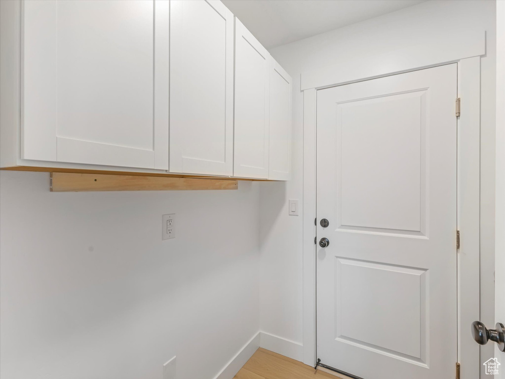 Washroom with baseboards, cabinet space, and light wood-style floors