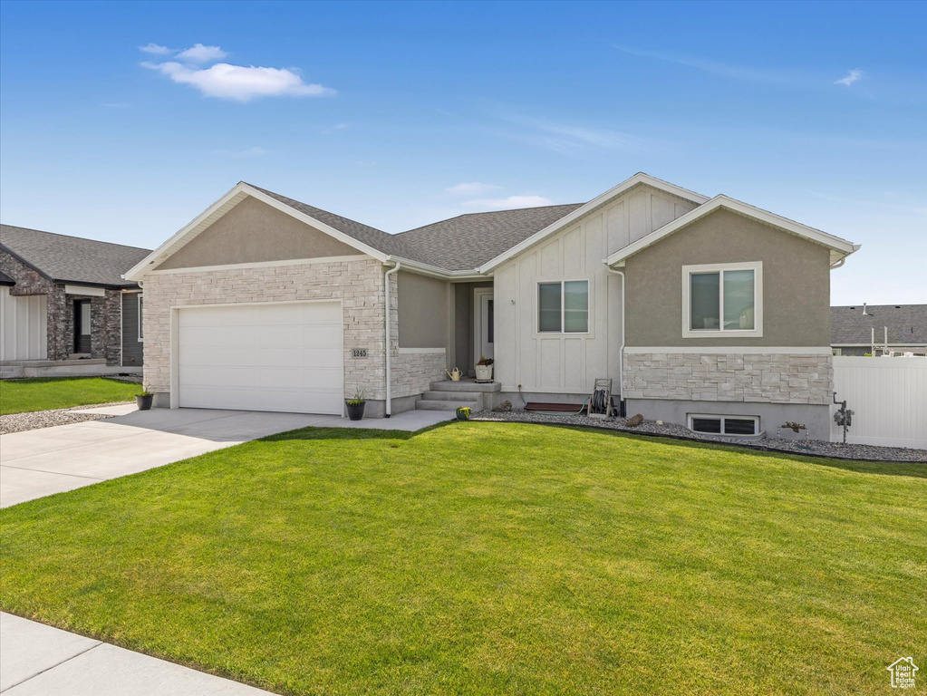 Single story home featuring stone siding, an attached garage, driveway, and board and batten siding
