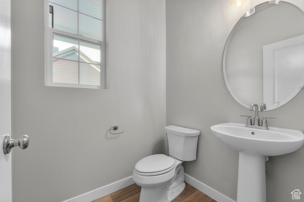 Half bath with baseboards, wood finished floors, and toilet