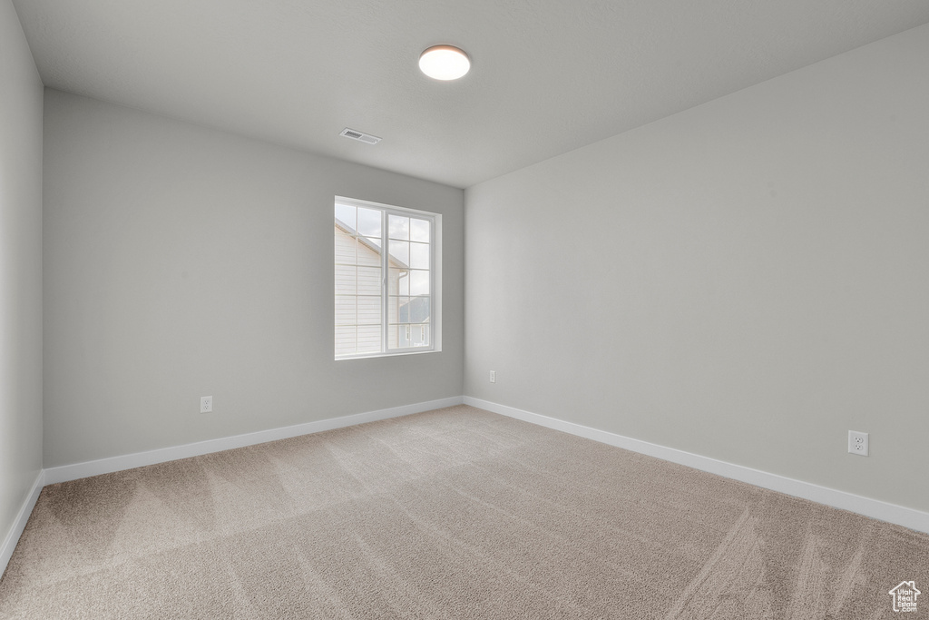 Empty room featuring light carpet and baseboards