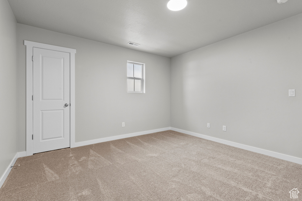 Carpeted spare room featuring baseboards
