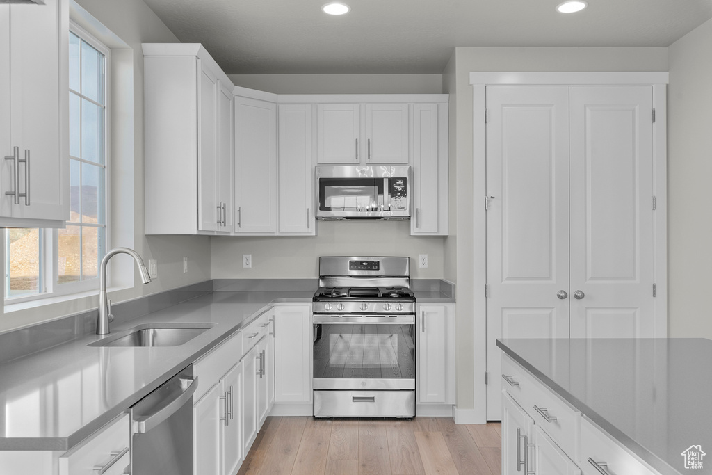 Kitchen featuring stainless steel appliances, a sink, healthy amount of natural light, recessed lighting, and white cabinetry