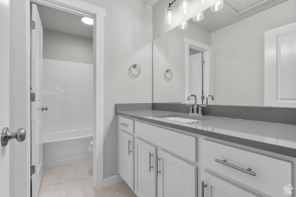 Bathroom with marble finish floors, vanity, toilet, and baseboards
