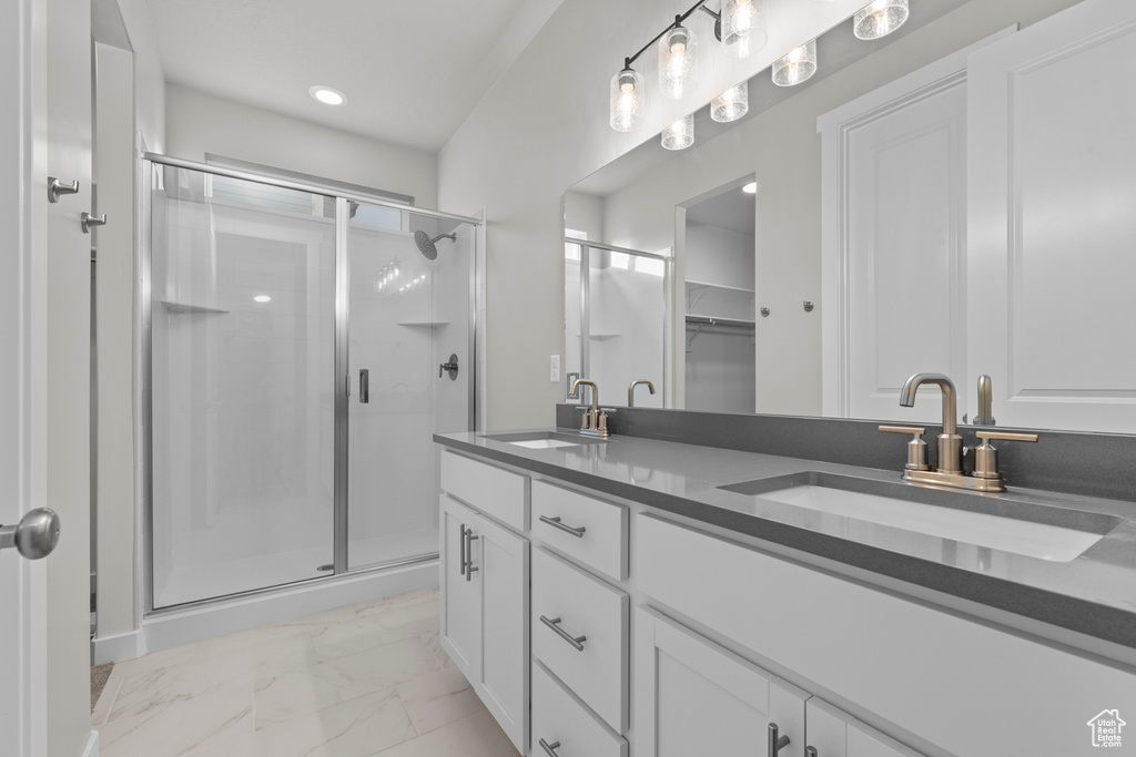 Bathroom with marble look tiles, a stall shower, double vanity, a walk in closet, and recessed lighting