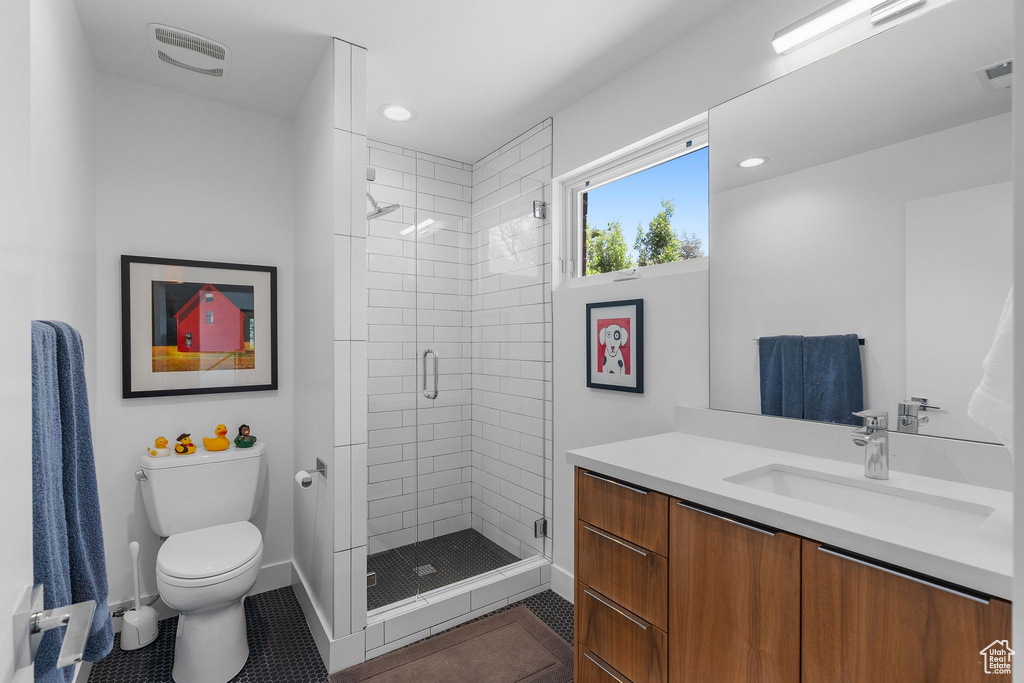 Full bath featuring tile patterned floors, toilet, a shower stall, vanity, and baseboards