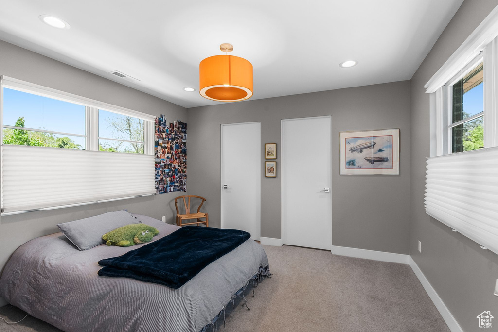Bedroom with multiple windows, light carpet, baseboards, and recessed lighting
