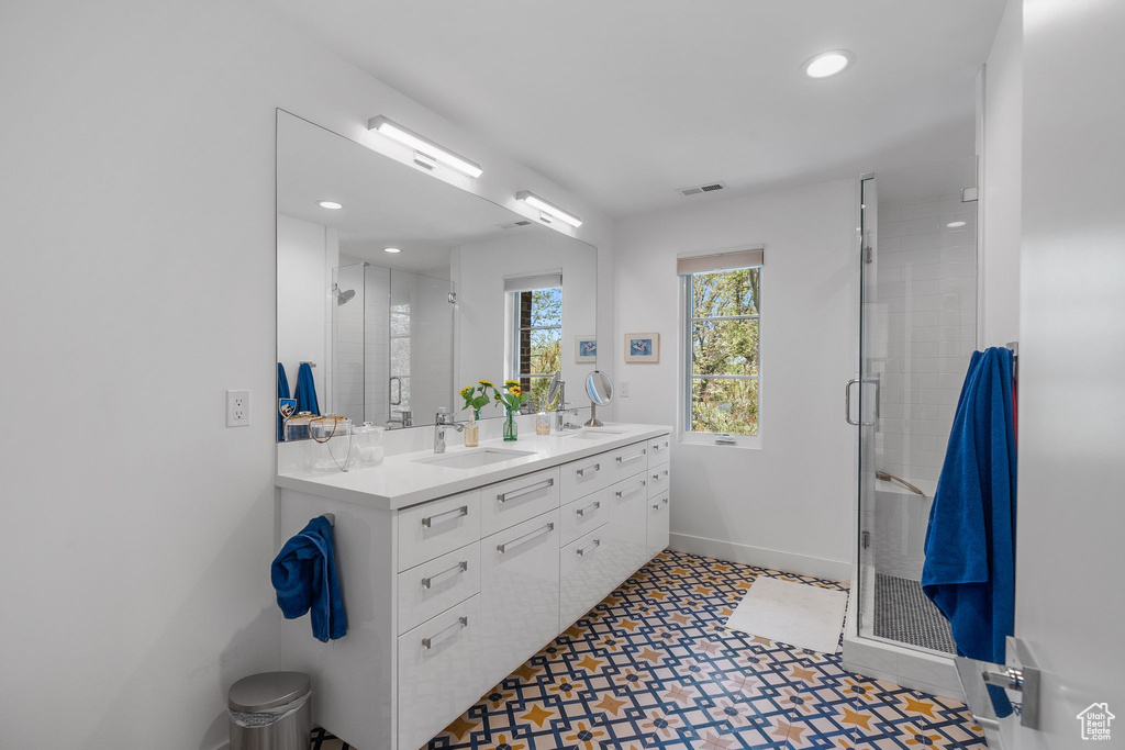 Bathroom featuring a shower stall, baseboards, double vanity, recessed lighting, and tile patterned floors