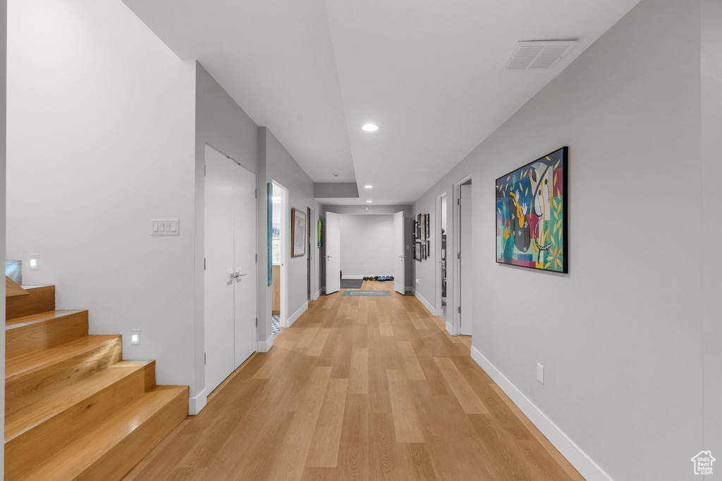 Hall featuring recessed lighting, light wood-style floors, baseboards, and stairs