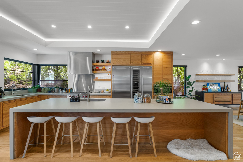 Kitchen featuring built in refrigerator, a sink, a raised ceiling, recessed lighting, and a spacious island