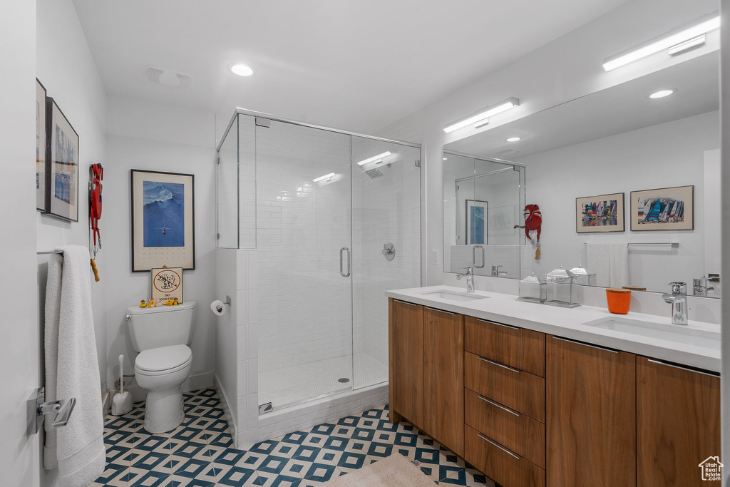 Bathroom with toilet, a stall shower, double vanity, tile patterned floors, and recessed lighting