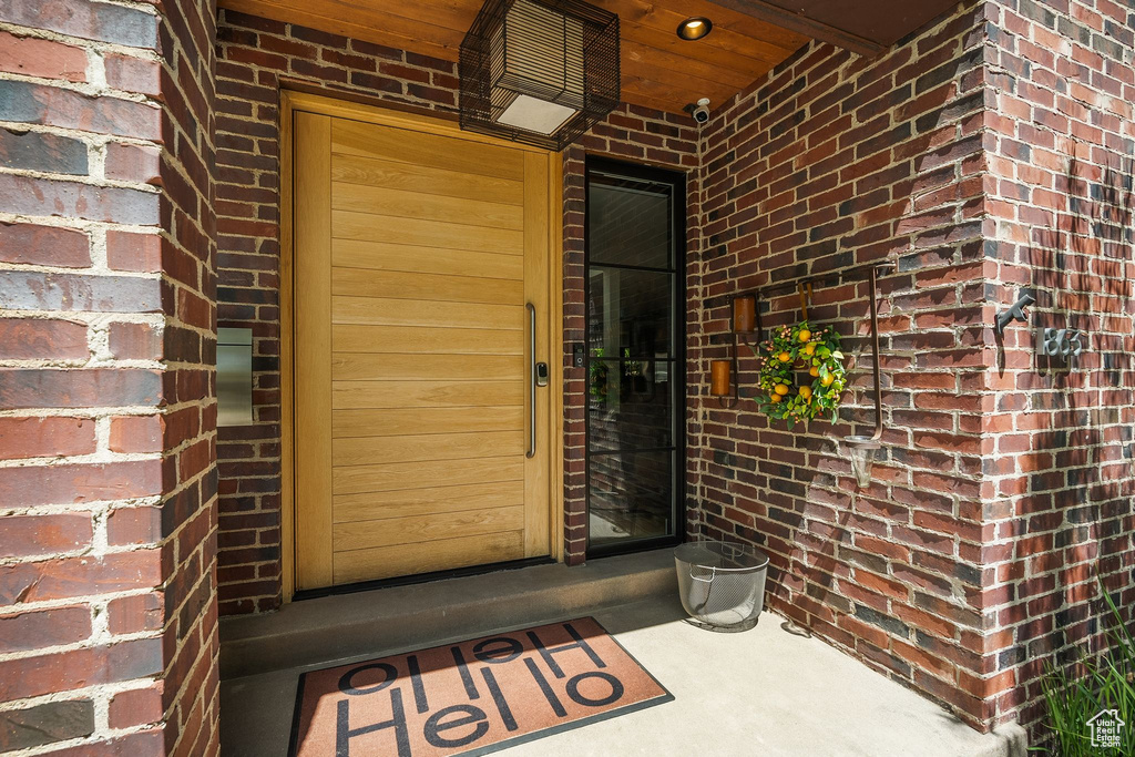 Doorway to property with brick siding and a security system