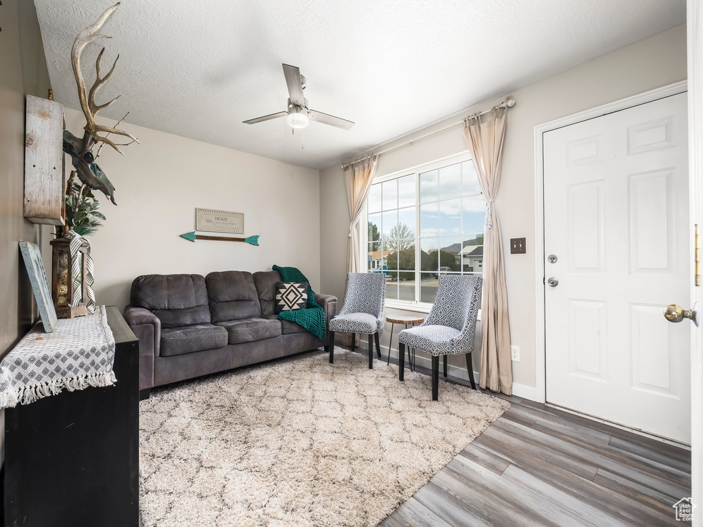 Living area with ceiling fan, wood finished floors, and baseboards