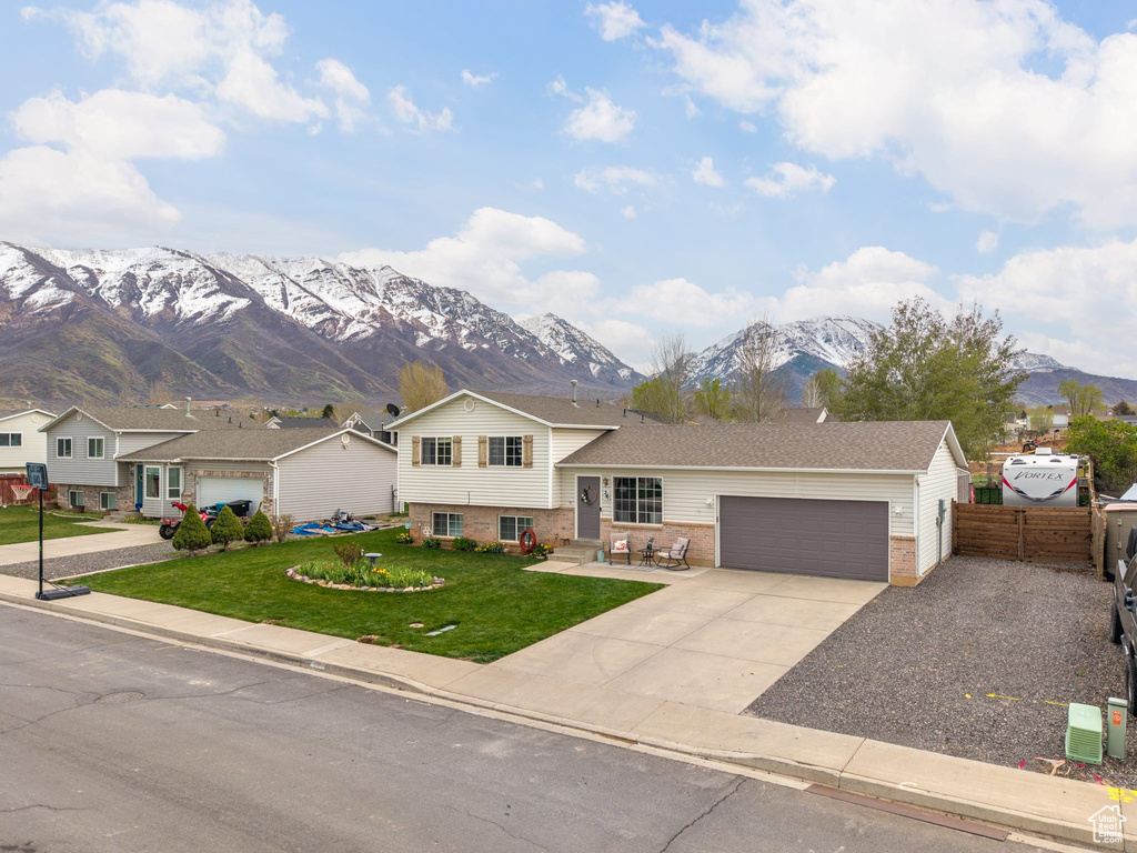 Tri-level home with a mountain view, an attached garage, brick siding, and concrete driveway