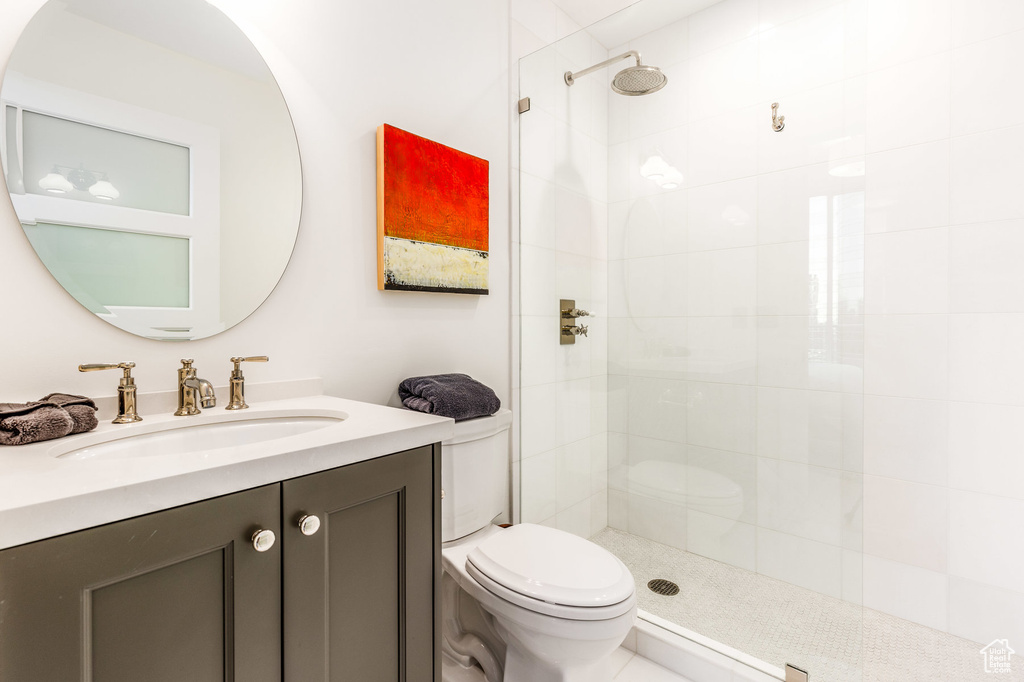 Bathroom featuring toilet, a tile shower, and vanity