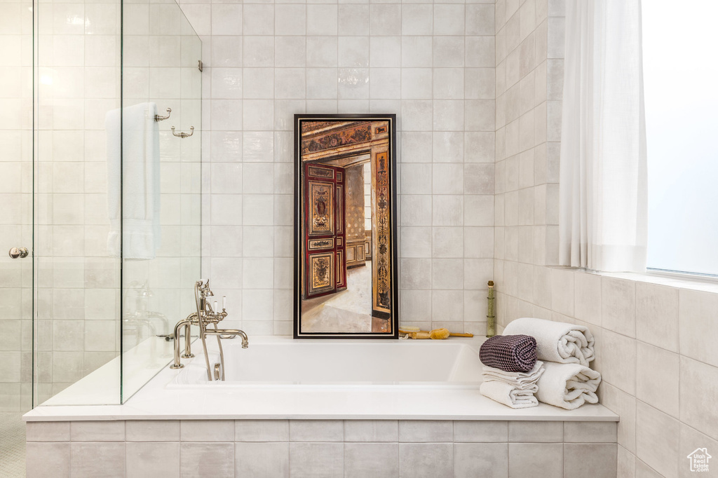 Full bathroom featuring tile walls, a bath, and tiled shower